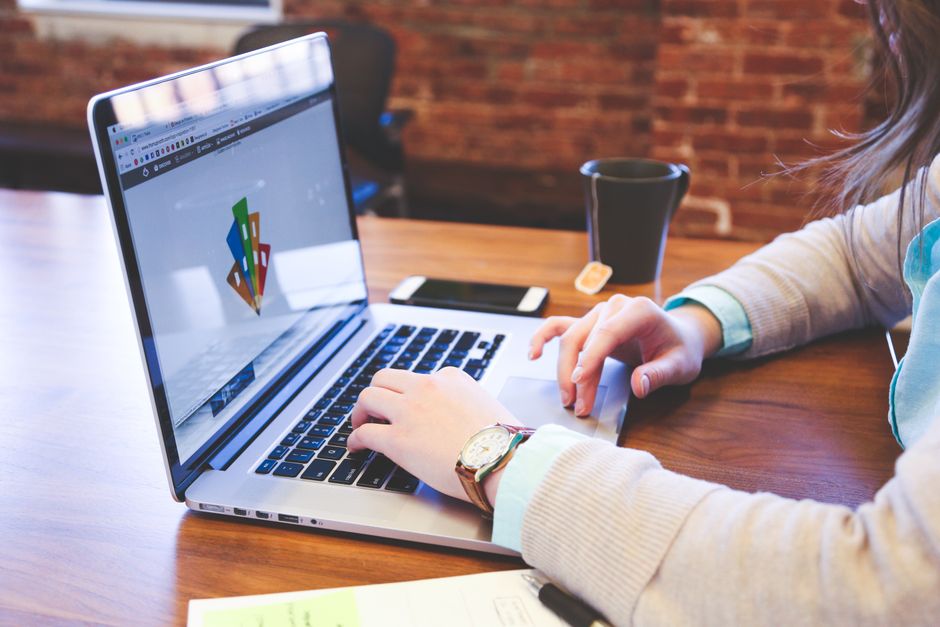 Mulher trabalhando em projeto de design utilizando laptop em um espaço moderno interno.